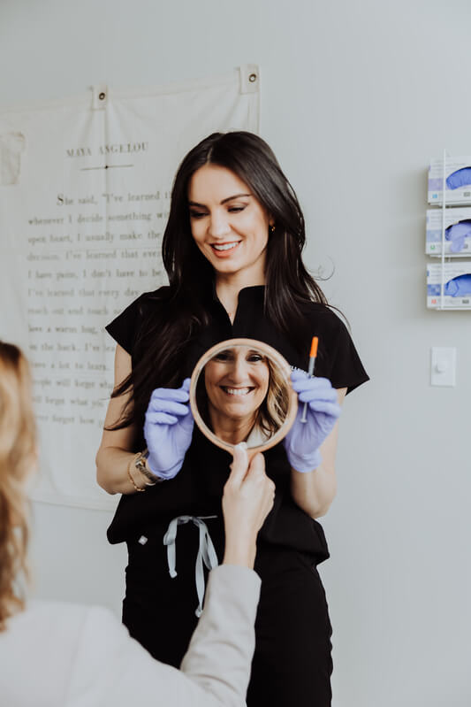 Esthetician showing mirror to the patient after treatment | Wellness Co. | Zeeland, MI